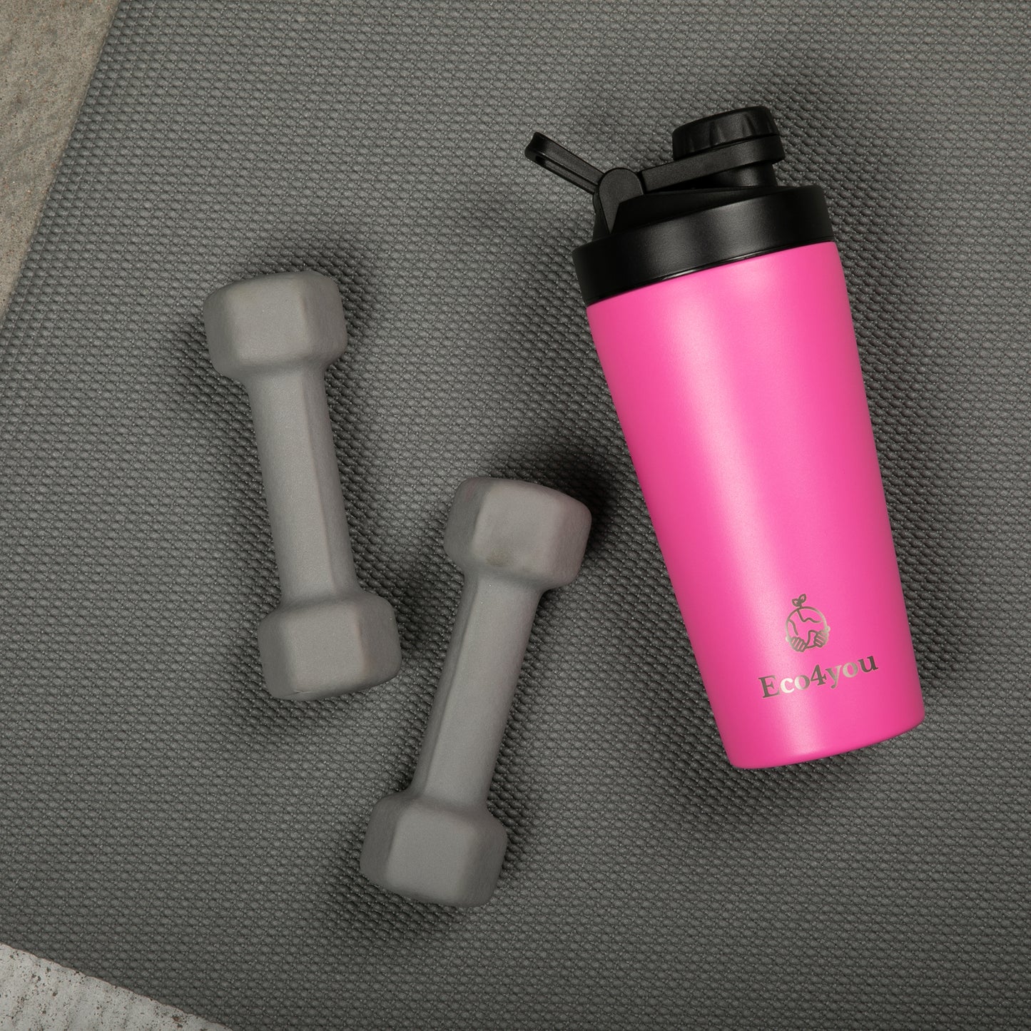 Eco4you pink stainless steel shaker bottle next to two gray dumbbells on a workout mat.